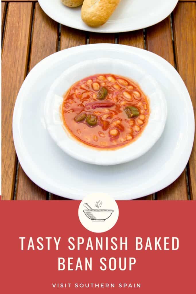 a pin with a bowl of Spanish Baked Bean Soup on a wooden surface.