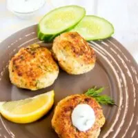 3 patties on a plate with cucumbers and lemon made with the jack Mackerel Recipe