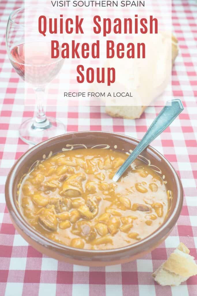 a pin with Spanish Baked Bean Soup in a bowl on a table.