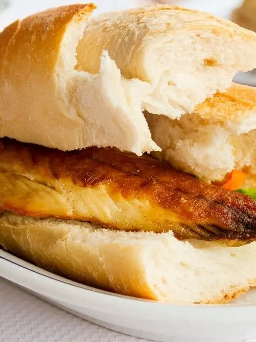 closeup of a mackerel burger recipe between 2 slices of bread.