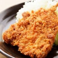 fried mackerel fish recipe served with white rice on a black plate