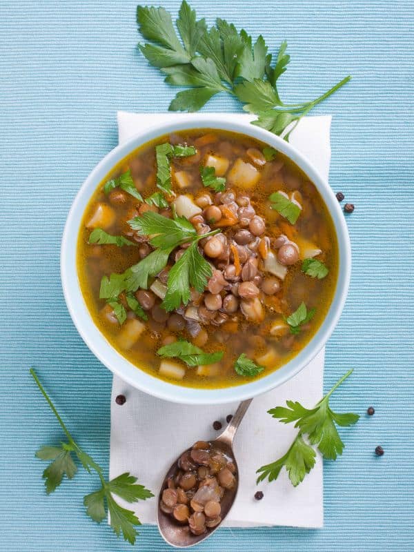 Spanish lentil soup with potatoes on a blue table