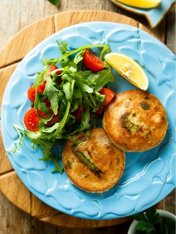 a plate containing 2 fish cakes served with salad made with the easy mackerel patties recipe
