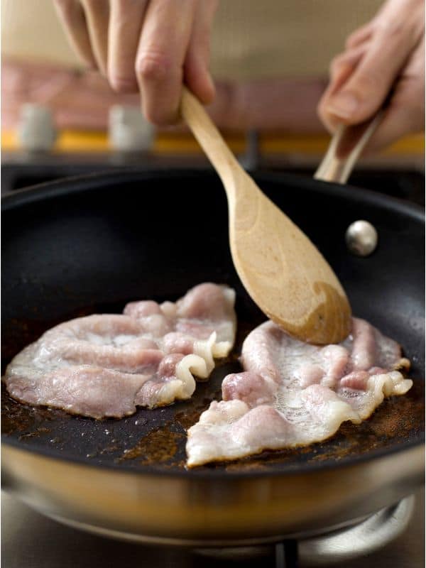 frying bacon in a pan for the Spanish bacon bean soup