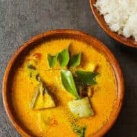 mackerel curry recipe in a clay bowl with rice on the side