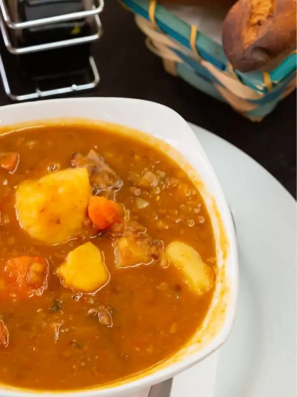 spanish lentil soup with chorizo and potatoes served in a white bowl