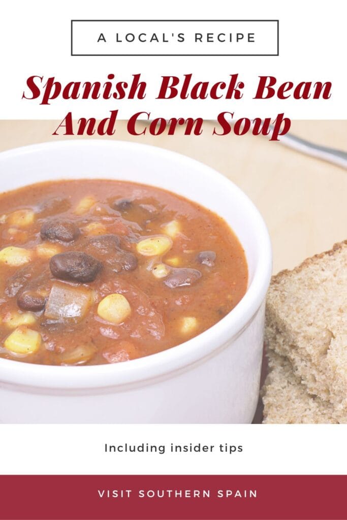 a pin with a bowl of Spanish black bean and corn soup served with bread.