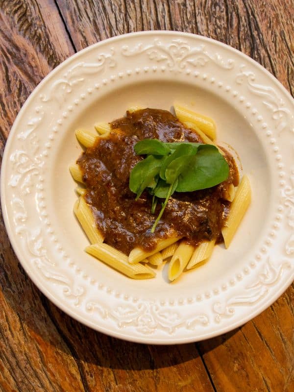 a bowl of oxtail pasta recipe decorated with basil