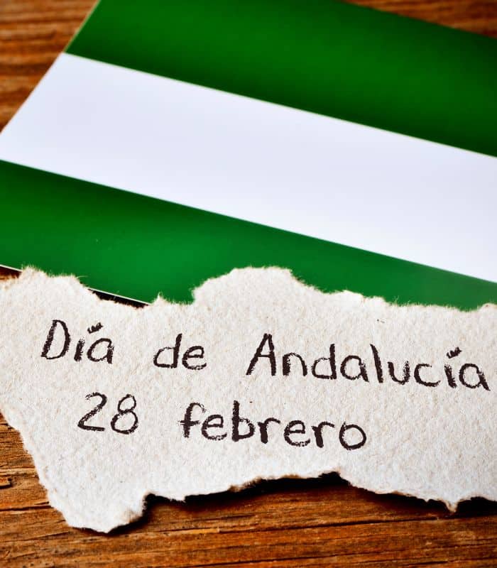 a piece of paper with dia de Andalucia written on it with Andalucia's flag in the background