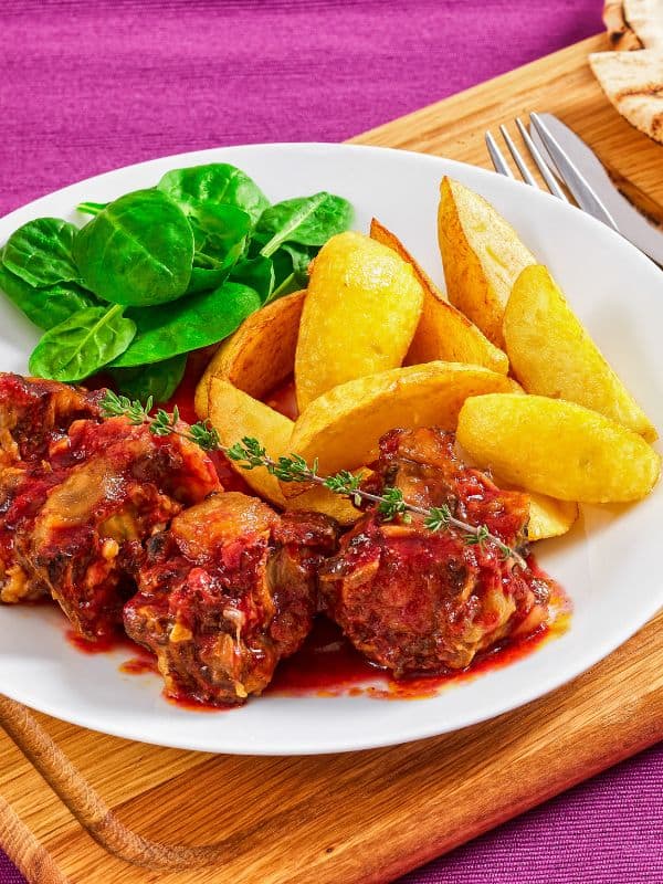 beef oxtail recipe served with potato wedges and salad