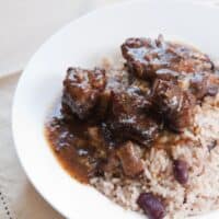 oxtail and butter beans served with rice and beans in a white bowl