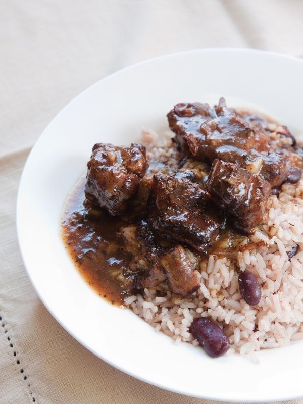 oxtails and rice with beans in a white bowl
