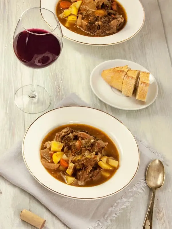 rabo de toro stew in 2 bowls with a glass of red wine