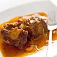 recipe for oxtails and gravy that's served on a white plate