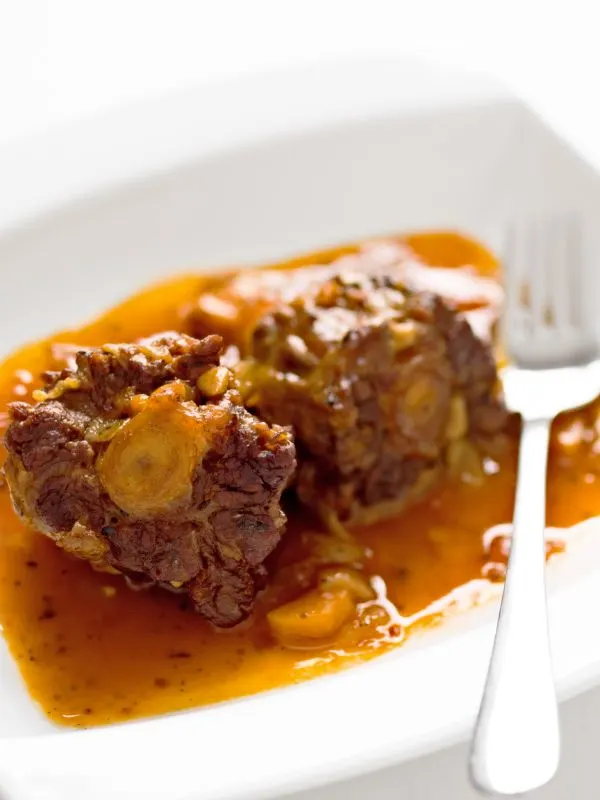 recipe for oxtails and gravy that's served on a white plate
