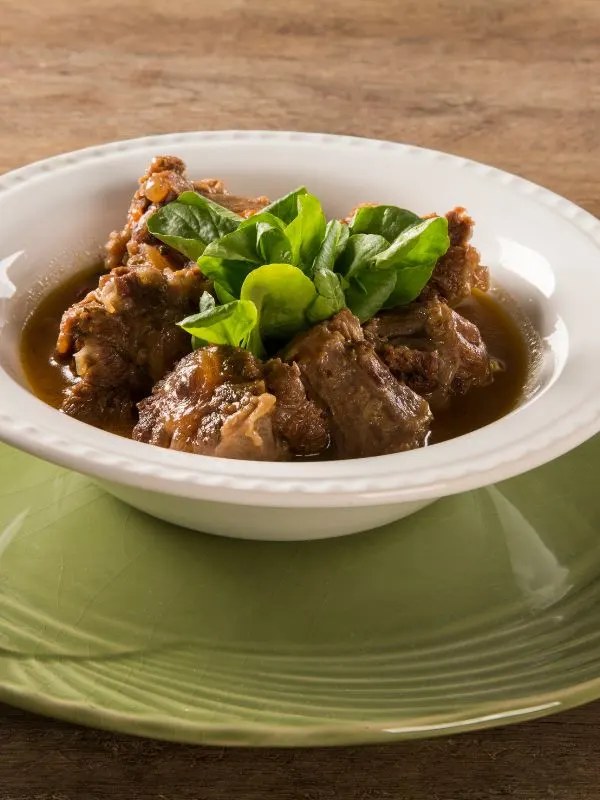 baked oxtails and gravy served in a white bowl