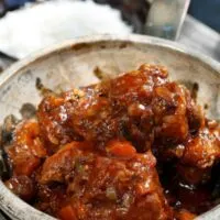 oxtail casserole with sauce in a pot with rice in the background