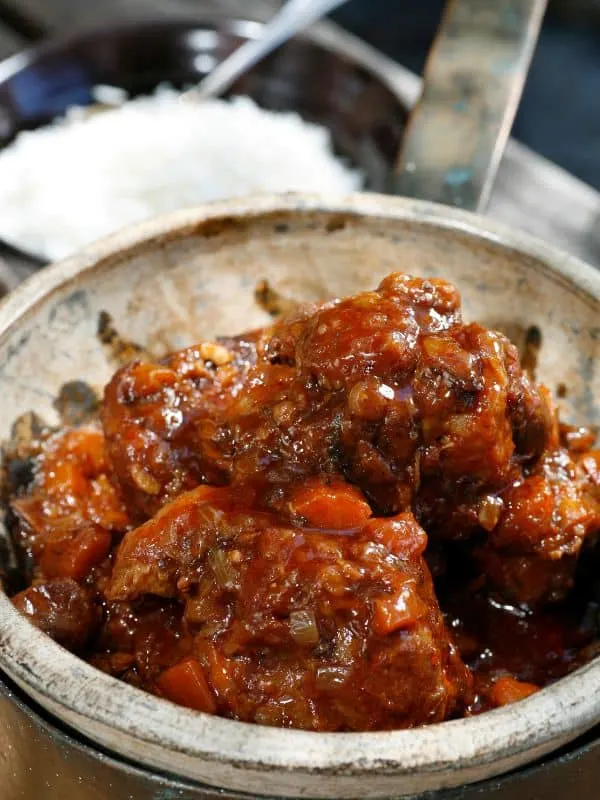red wine oxtail stew in a pot with rice in the background