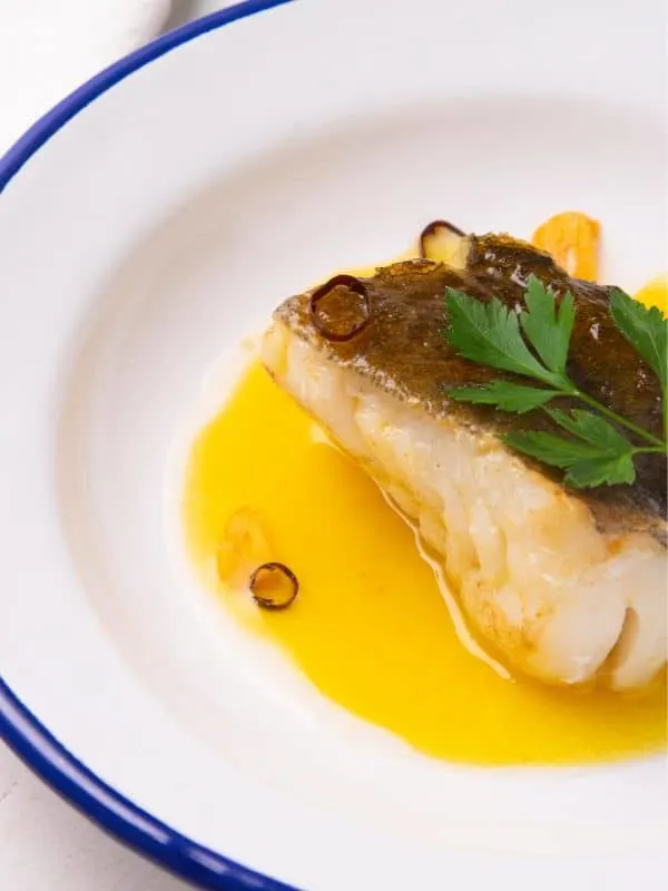 Bacalao al Pil-Pil served with olive oil sauce in a plate