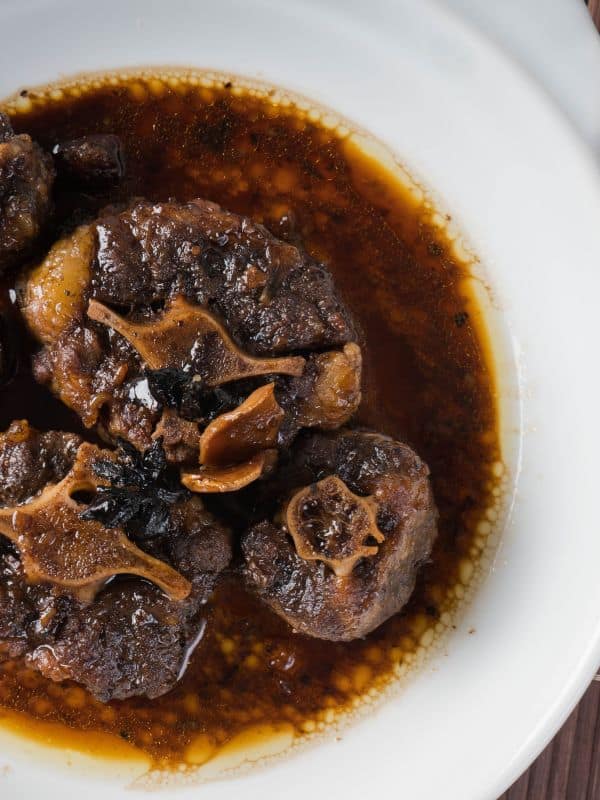 red wine braised oxtail served in a white plate and made with the oxtail marinade recipe