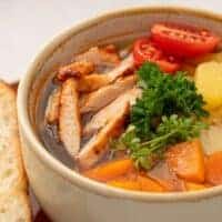 a bowl of Chicken Soup Without Noodles with potatoes, carrots and parsley