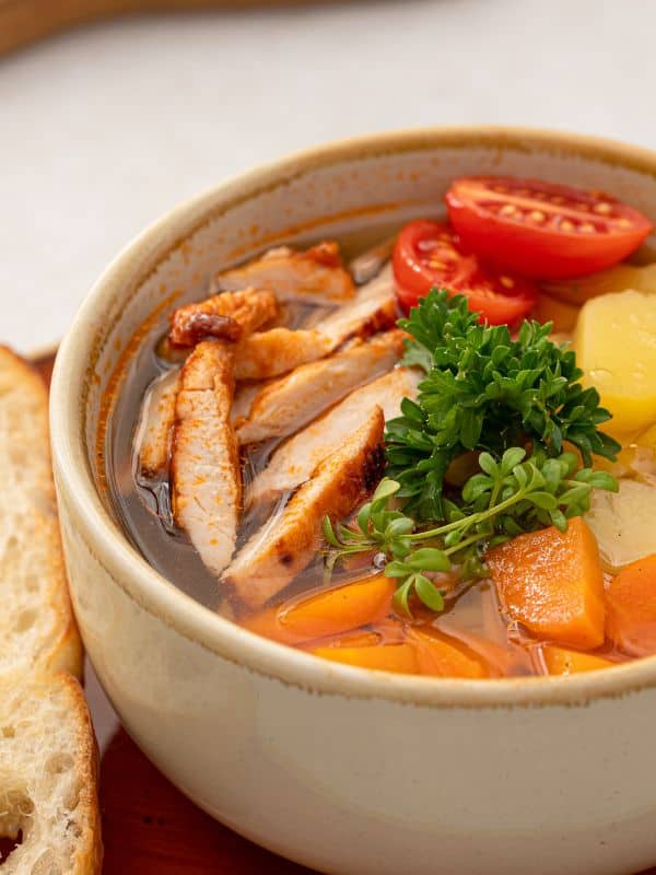 a bowl of Chicken Soup Without Noodles with potatoes, carrots and parsley