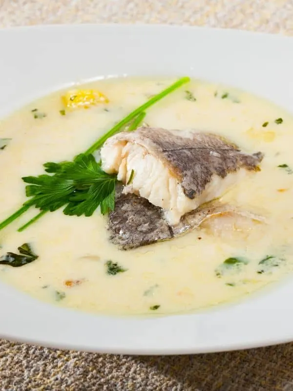 creamy white fish soup served in a bowl with parsley on top
