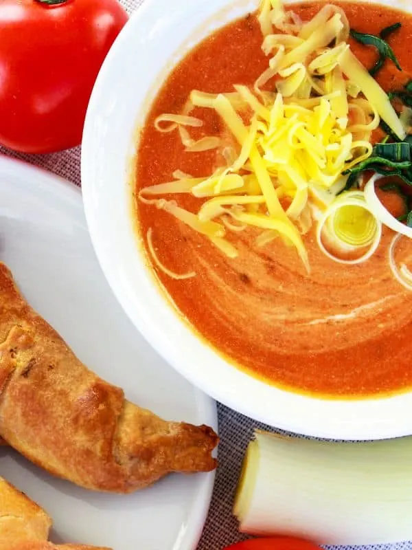 Tomato Leek Soup in a bowl served with cheese and bread