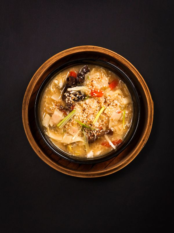a bowl of glass noodle soup with mushrooms and chicken