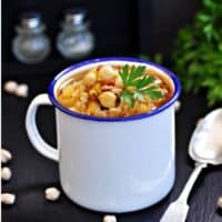 a cup with Cuban Garbanzo Bean Soup on a black surface