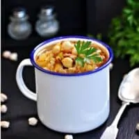 a cup with Cuban Garbanzo Bean Soup on a black surface