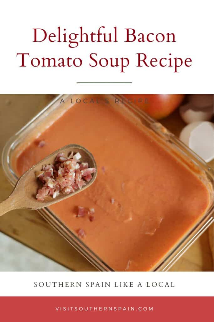 a pin with a glass bowl of Bacon Tomato Soup with a spoon of bacon