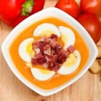 Cordoba Tomato Soup with boiled egg and bacon and pepper, tomatoes next to it.