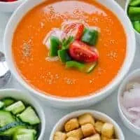classic gazpacho recipe in a bowl with fresh vegetables next to it