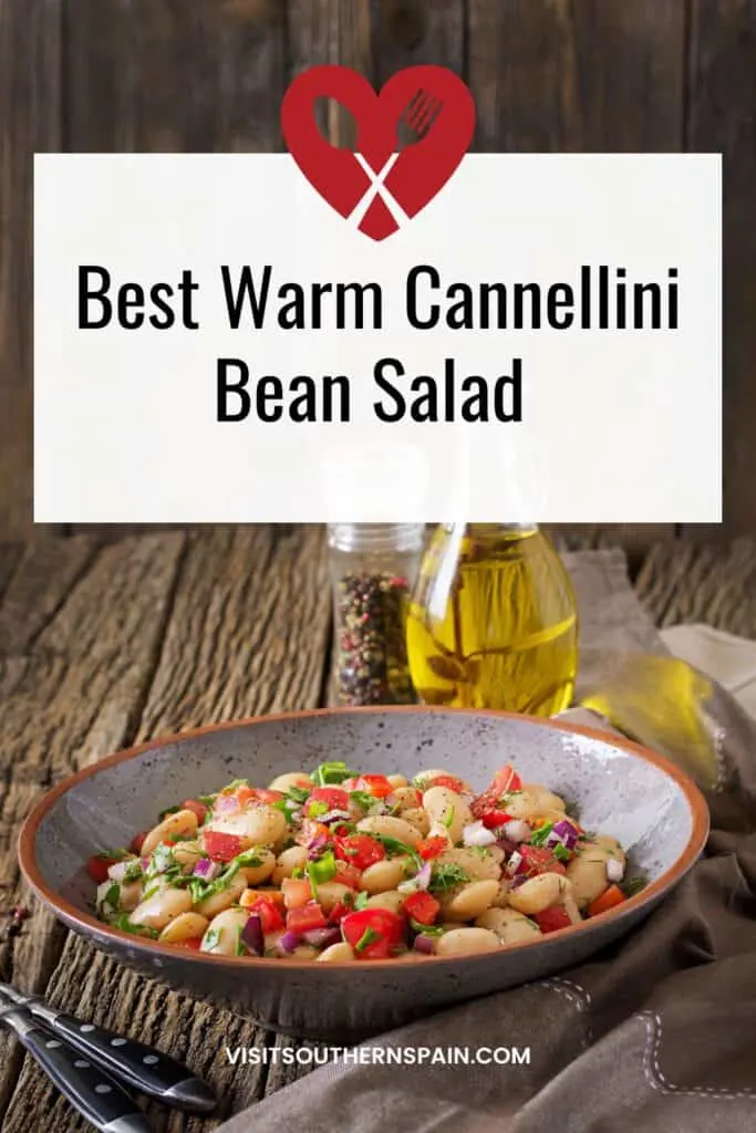 a pin with warm cannellini bean salad in a bowl next to a bottle of olive oil