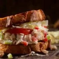 chicken salad recipe with yogurt between 2 toasts on a wooden board.