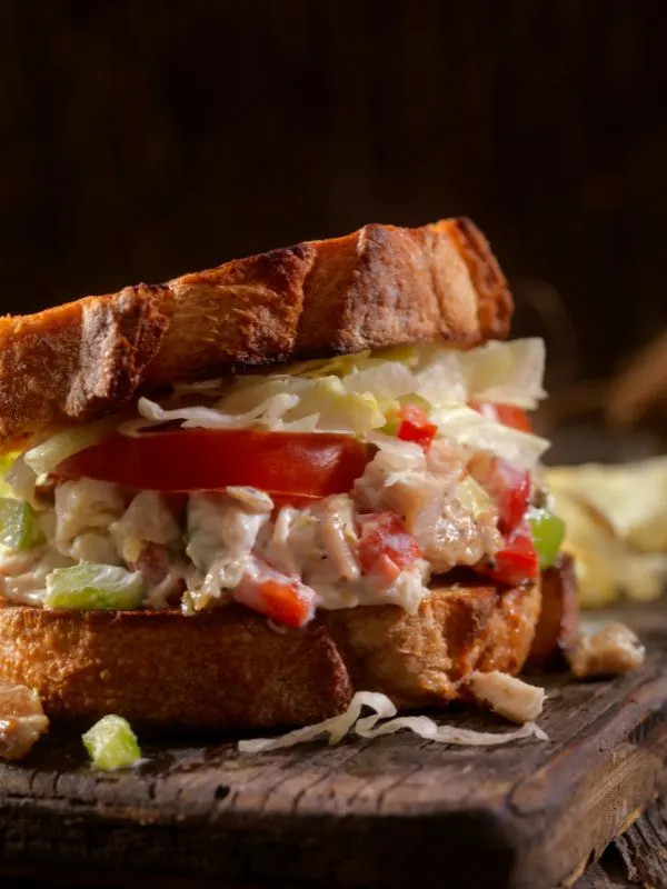 chicken salad recipe with yogurt between 2 toasts on a wooden board.