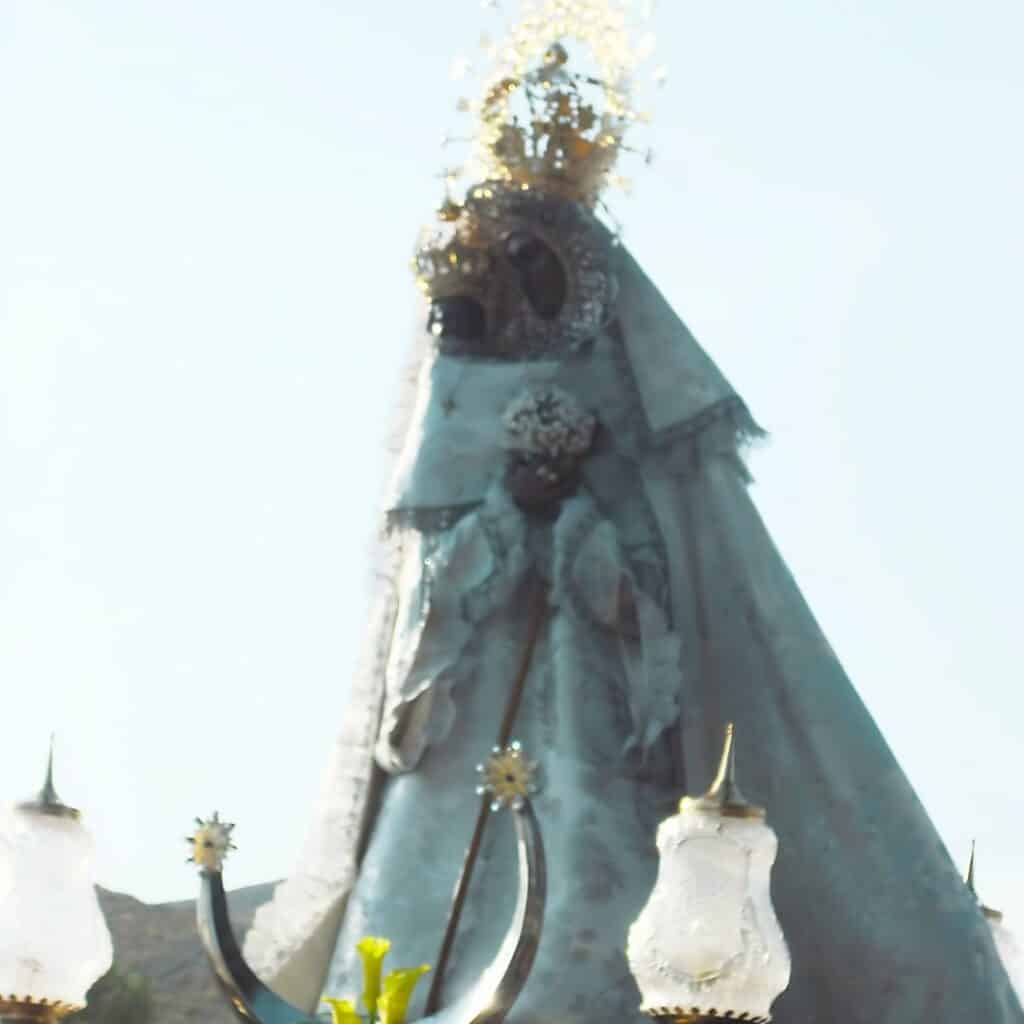 an image of the blessed virgin mary carrying a child with white gown and crown being paraded