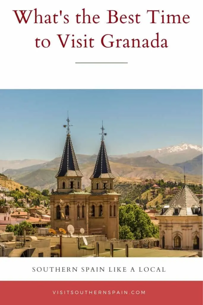 a view of an old town with two towers peaking and mountains in the background