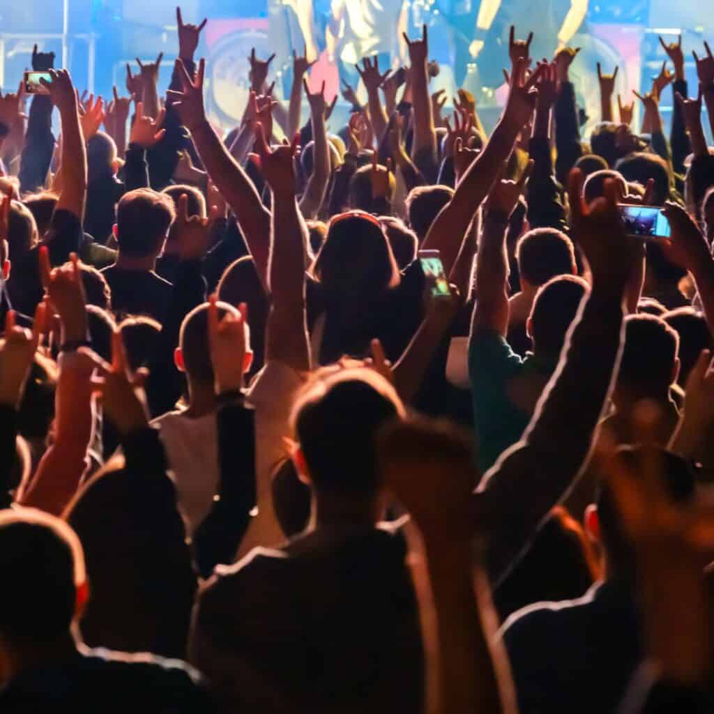 a crowd of people at a concert with their hands up in the air