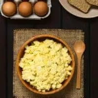 spanish egg salad in a clay bowl with eggs and toast next to it.