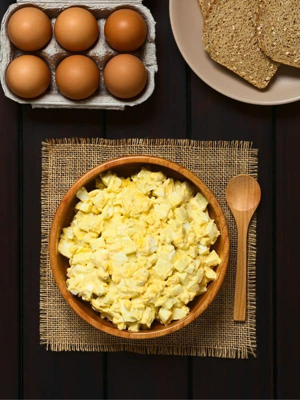 spanish egg salad in a clay bowl with eggs and toast next to it.