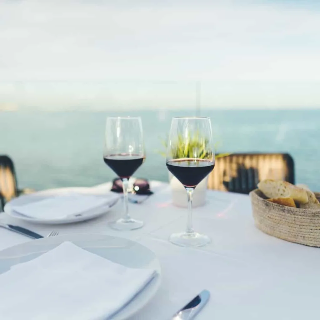 two glasses of wine on a table with a view of a body of water