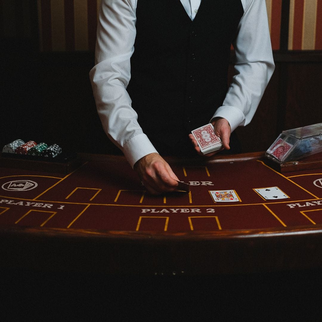 a person in a vest and tie playing cards on a casino table