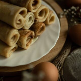 Frixuelos de Asturias rolled on a plate with eggs around them
