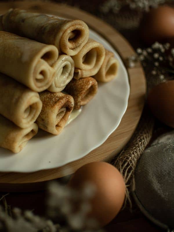Frixuelos de Asturias rolled on a plate with eggs around them