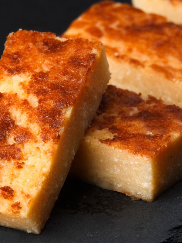 Quesada Pasiega cut into bars served on a black plate