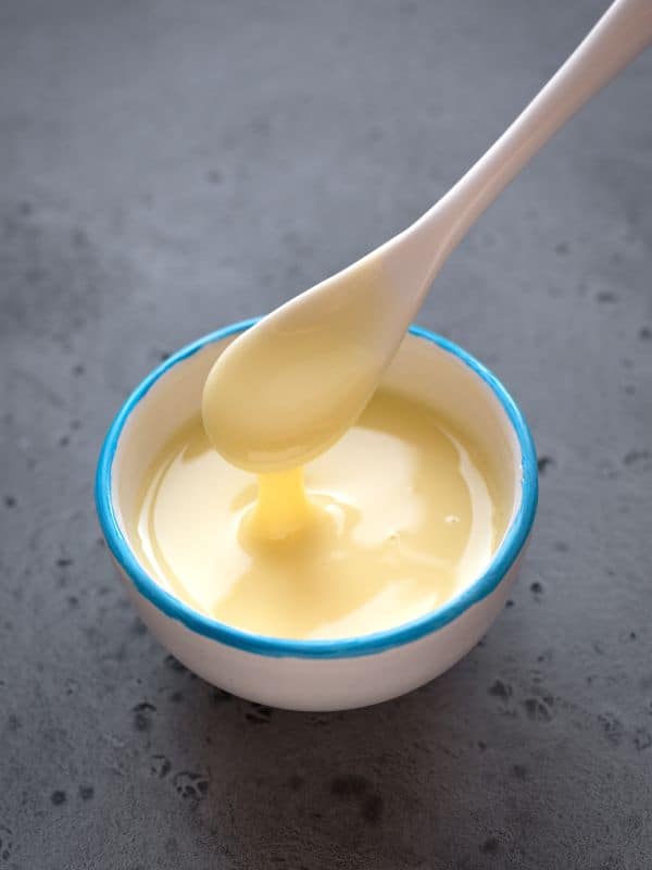 condensed milk in a small bowl with a spoon for the Tarta de Lim&oacute;n