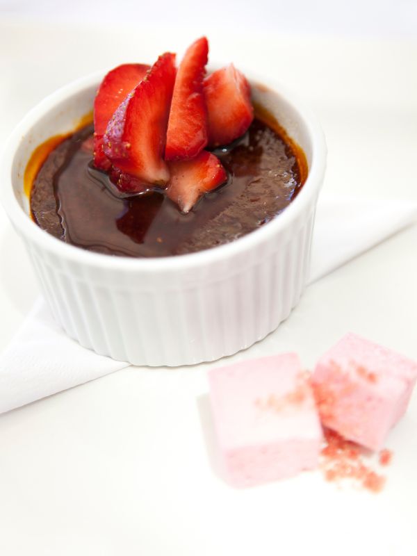 Chocolate Crema Catalana in a white bowl topped with strawberries