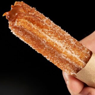 closeup with Dulce de leche churros held in hand